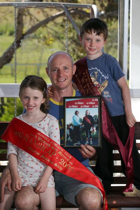 Jayne’s husband Carl McMeel and their children Hannah, 5, and Leo, 4, with her winning sash and photo taken with Cathy Freeman at the Stawell Gift in 2000.