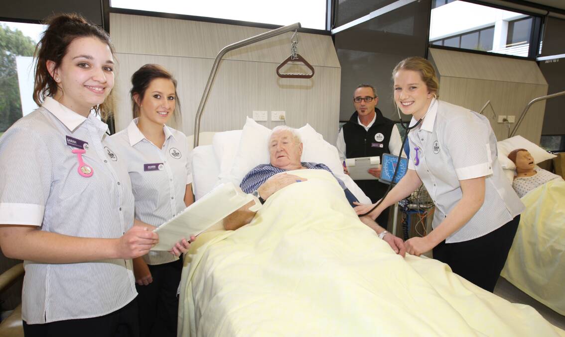 “Patient” Gerry O’Brien has his blood pressure taken by first-year nursing student Sarah Anderson (right) as Sarah Smith and Marni Young take notes and Deakin University School of Nursing lecturer Chris Wakefield observes.