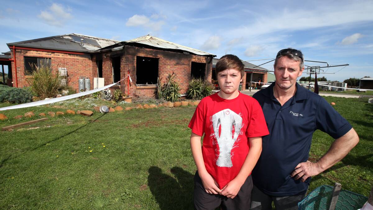 Mark Hand stands outside the blackened remains of his home with his son Jordan, 14, who was inside asleep when the fire  broke out.
