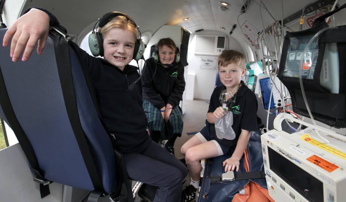 Koroit and District Primary School students Ava Sharman, 10, Keira Longmore, 8 and Connor Byrne, 9, sit inside the Royal Flying Doctor Service simulator during a visit to the school. Picture: ROB GUNSTONE 