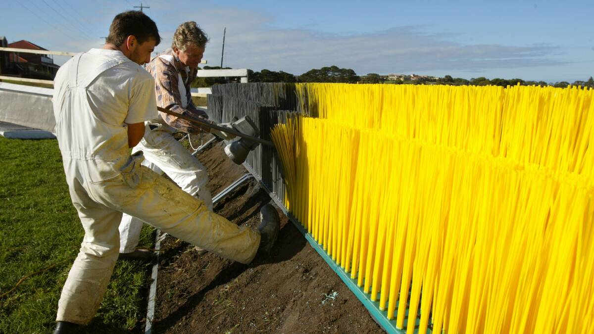 Painter Tony Lunn (left) abd Shane Mahony turn the spraygun on one of the new synthetic steeples at the Warrnambool Racecourse, turning them into a more natural brush colour. 