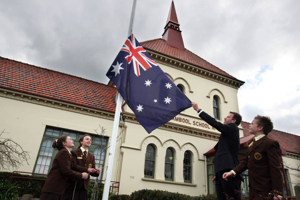 Warrnambool Primary School junior school council members Ruby Bilson, 12 (left), Maudie Reading, 12, and Bailey Philp, 12, help Wannon MP Dan Tehan unveil the new flag in preparation for Australian National Flag Day. 140821LP44 Picture: LEANNE PICKETT