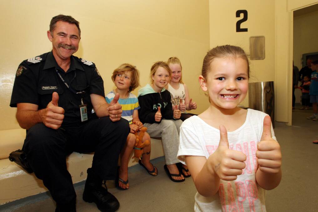 Senior Sergeant Russell Tharle shows Maxwell, 5, and Charlotte Dance, 7, from Port Fairy, and Mia Stephen, 9, and Macey Bolden, 6, both from Warrnambool, through the cells. 141018LP09  Picture: LEANNE PICKETT