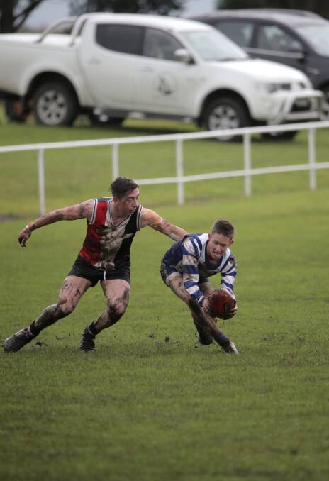 Koroit’s Taylor Mulraney tries to grab hold of Hamilton Kangaroos’ Jon Manson in slippery conditions. Picture: VICKY HUGHSON