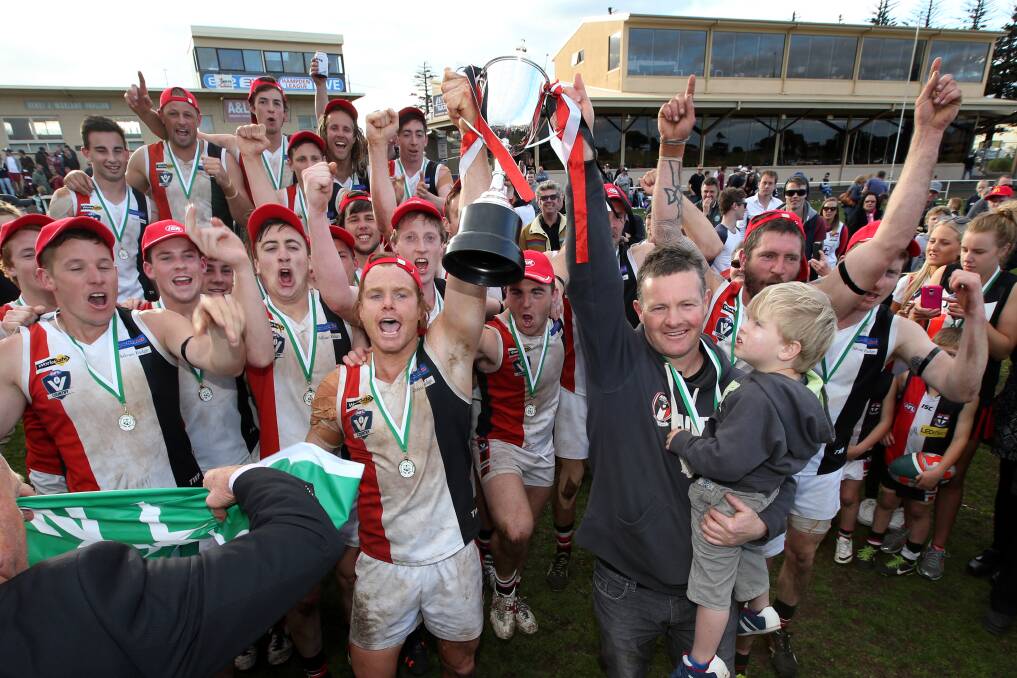 Coach Adam Dowie hoists the premiership cup with captain Isaac Templeton, surrounded by a jubilant playing group. Dowie said the Saints’ upset win over Warrnambool was one of the most memorable of his career. 140920DW32 Picture: DAMIAN WHITE