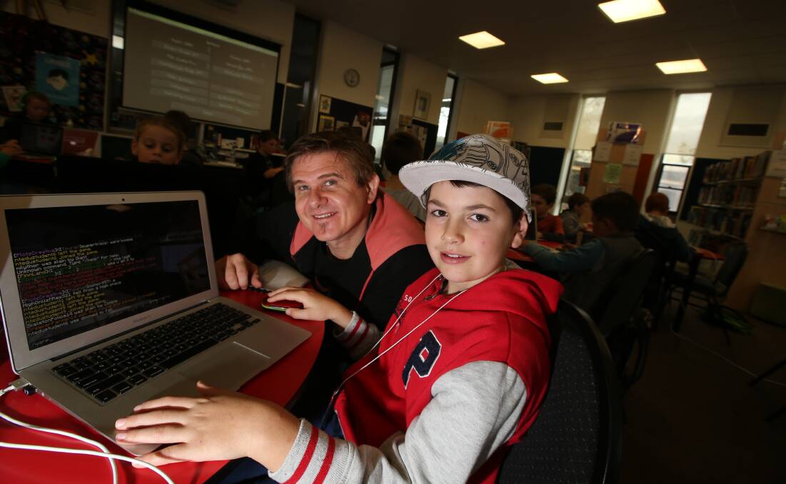 Minecraft camp co-ordinator Tim Wicks helps Jayden Bell, 10, with a challenge at yesterday’s event. 