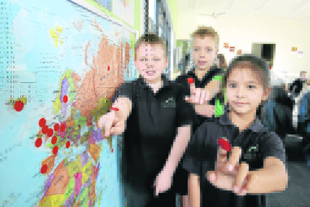 Brothers Kevin, 8 (left), and Michael White, 11, originally from Ireland, and Fern Knowles, 8, originally from Thailand, place stickers on a map of the world as Koroit and District Primary School pupils plot their family heritage as part of class studies. 140716RG02 Picture: ROB GUNSTONE