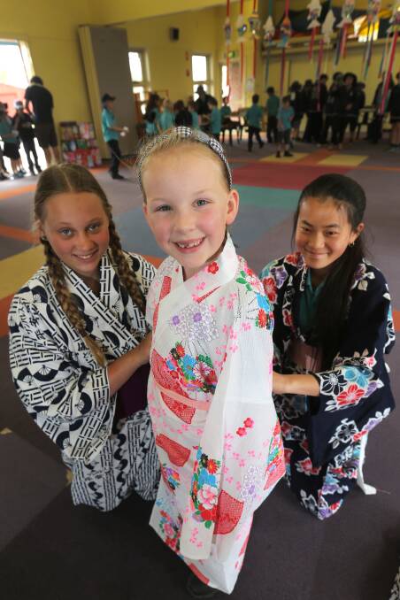 Grade 6 pupils Rehn Laidlaw, 12 (left), and Guan Bright, 11 (right), help Remy McInerney, 7, into a traditional outfit at West Warrnambool Primary School’s Japanese Festival yesterday. 141126RG13 Picture: ROB GUNSTONE
