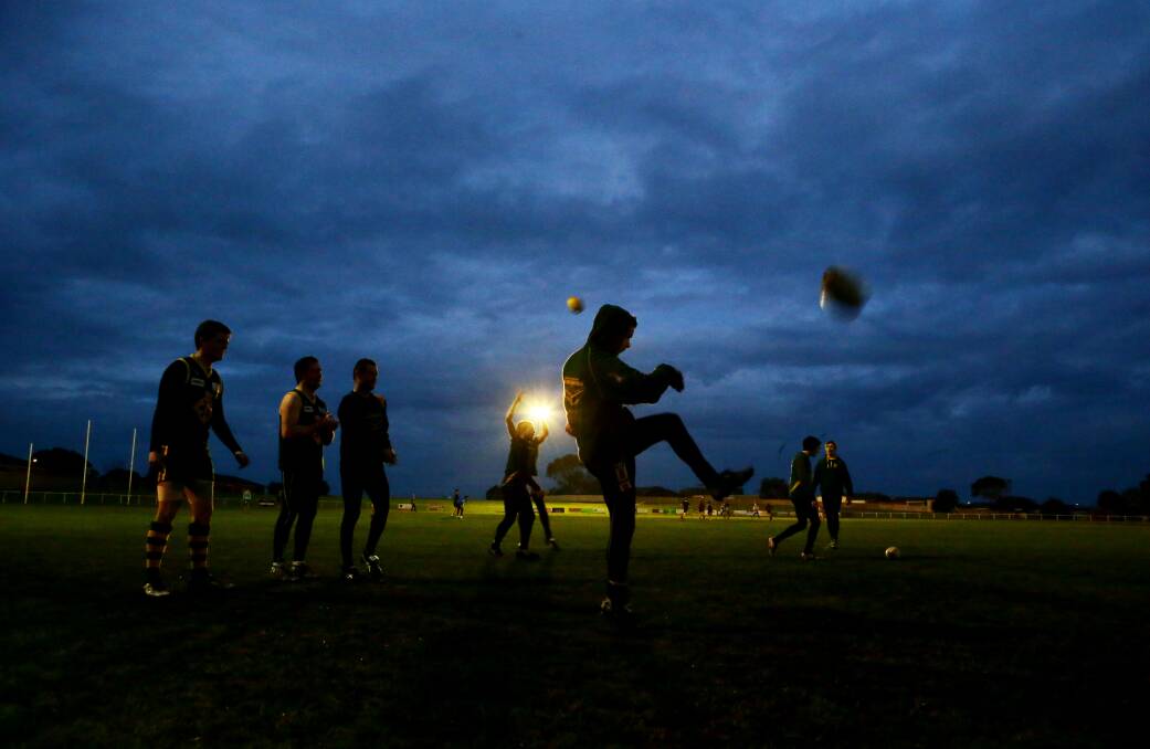 Warm-up drills begin at Davidson Oval in rapidly-fading twilight as Old Collegians players hit the track.140724LP26 Picture: LEANNE PICKETT