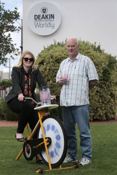 Deakin University administration assistant Amy Armstrong powers up the smoothie bike for Warrnambool head of campus Gerry Quinn. 