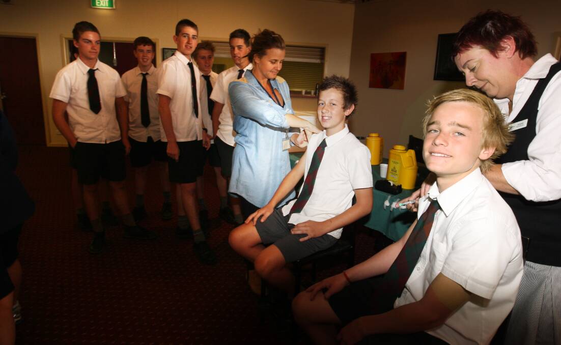 Immunisation nurses Nicole McCarthy (blue shirt) and Amanda Flanagan vaccinate students Beau Dignan, 12, and Daniel Nevill, 12, respectively at Brauer College’s Anderson Theatre.