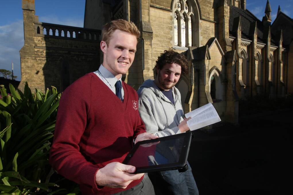 Stuart Pike (left) accesses the Bible using an iPad while Matt Graham takes the traditional route at Warrnambool’s St John’s  Presbyterian Church. 140430AS05 Picture: AARON SAWALL