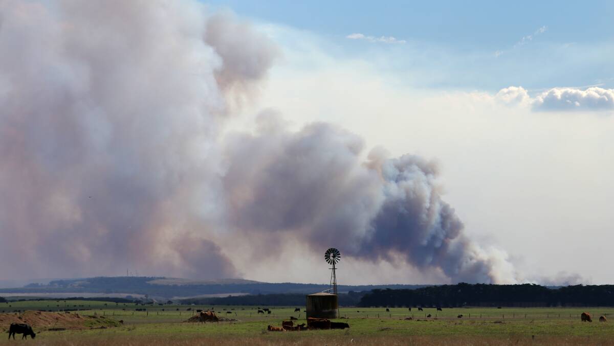 Smoke billows on the horizon as an out-of-control fire burns towards Narrawong yesterday.
