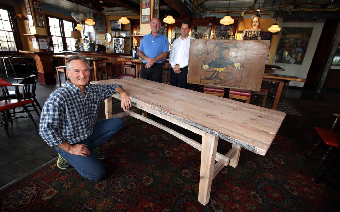 Gordon Lanman, from Lanman Fine Furniture, with the table he handcrafted from timber salvaged from the former Criterion Hotel. Stephen Phillpot, one of the owners of the Criterion Hotel, and Bryn Murfett’s brother Rohan look on. 