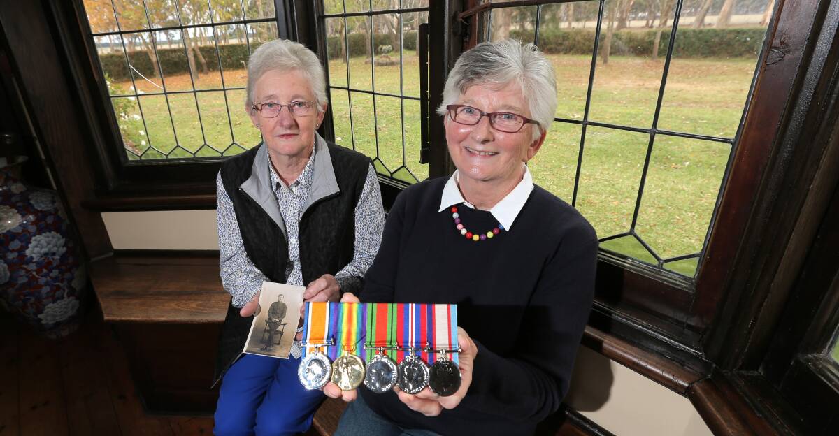 Mary Keogh, 75 (left), holds a picture of her late father Hubert “Leo” Campbell, while her sister Gloria Dickson, 81, holds his WWI medals that she will wear at today’s Anzac Day march in Melbourne. Picture: AARON SAWALL