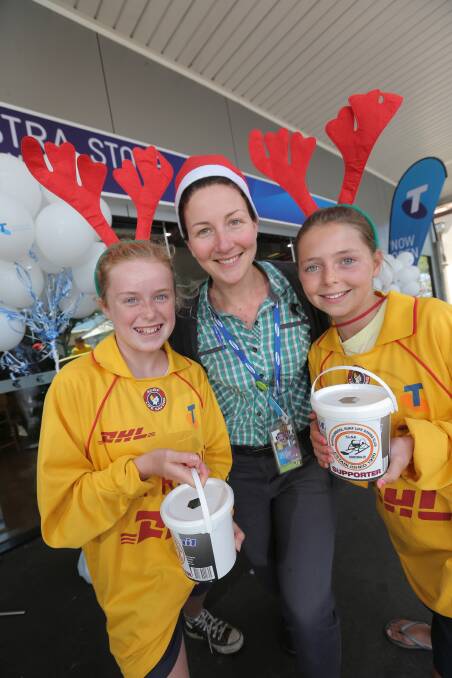 Clancy McCoy, 12 (left), and Molly O’Brien, 12,  show Telstra store manager Melina Sobey the rewards of the work.141220VH04 Picture: VICKY HUGHSON