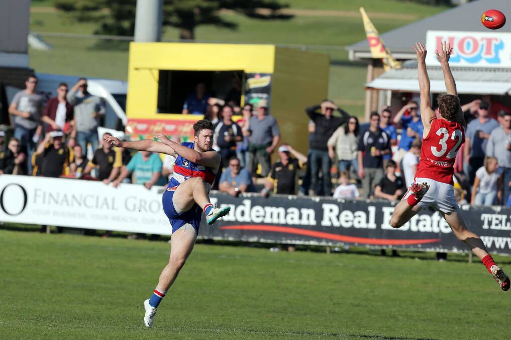 Panmure’s Daniel Roache kicks over a leaping Luke Moutray of Dennington during Saturday’s preliminary final at Reid Oval.  140830LP04 Pictures: LEANNE PICKETT