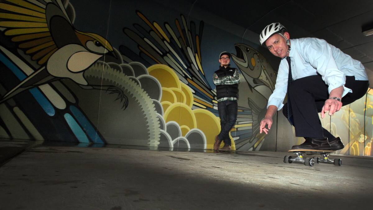 Warrnambool City mayor Michael Neoh tries out his skateboard in the transformed Russells Creek underpass watched on by artist Scottie Neoh. 140801LP30 Picture: LEANNE PICKETT