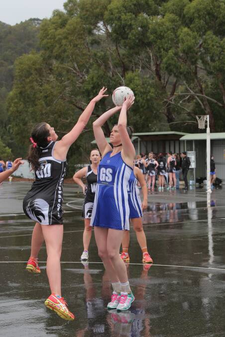 Camperdown goal defence Brooke Richardson leaps to spoil a shot by Hamilton goal shooter Kelsey Lewis in the wet conditions at Leura Oval on Saturday. 140509VH11 Pictures: VICKY HUGHSON