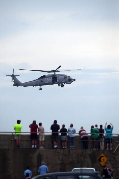 People gathered to watch the HMAS Melbourne at Lady Bay, while a Seahawk helicopter hovered around and let off a flare.