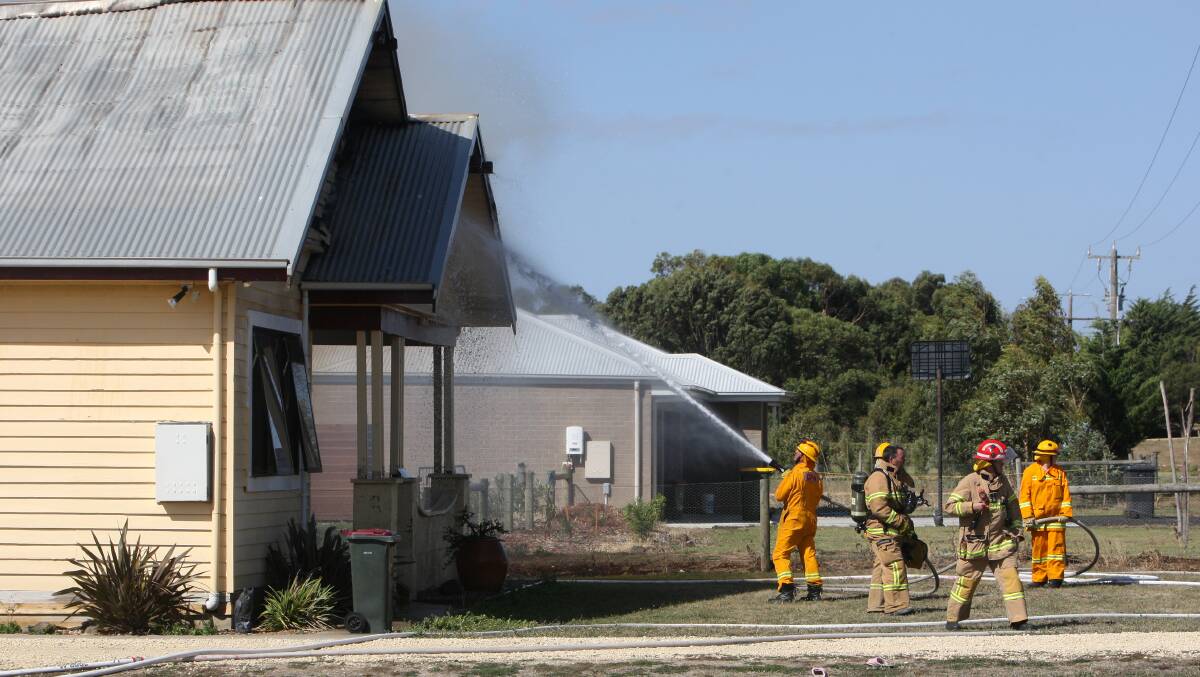 Firefighters hose down the burning house on Wangoom Road. 