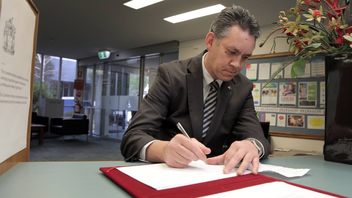 Warrnambool mayor Michael Neoh yesterday adds his name to an official condolence book for the relatives of victims of the MH17 airliner tragedy. 