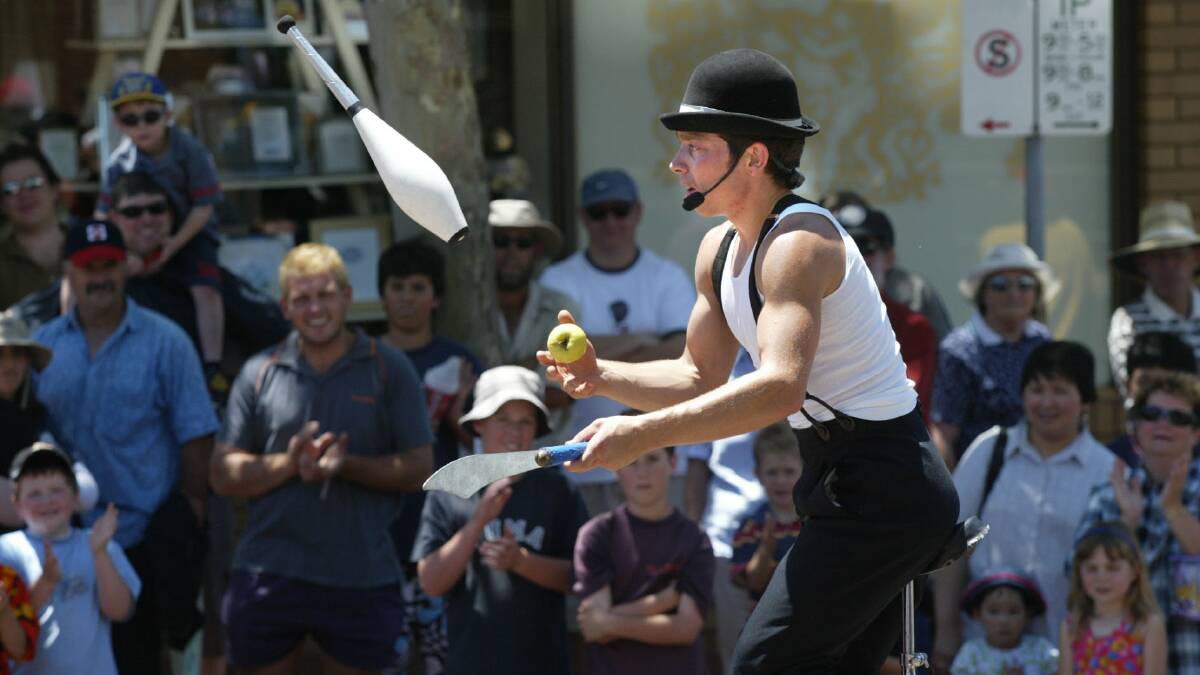 Melbourne juggler Daniel Oldaker with an apple, knife and club on a unicycle.