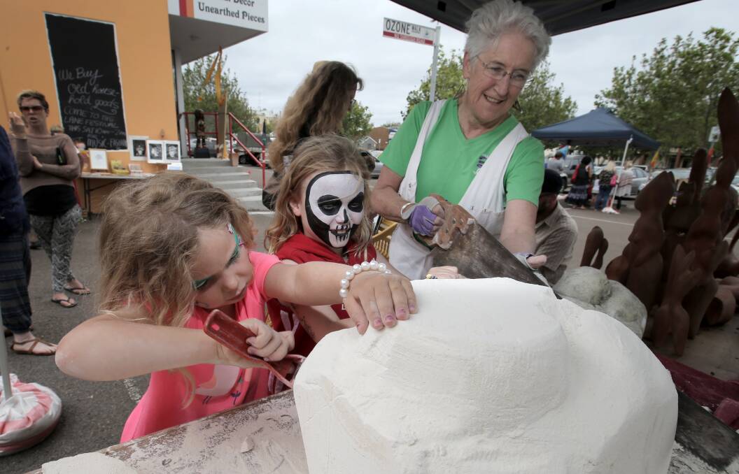 Sisters Stella Ryan, 6, and Maya Ryan, 8, of Warrnambool, help local artist Merran Koren with her sculpture, during the Laneway Festival. 