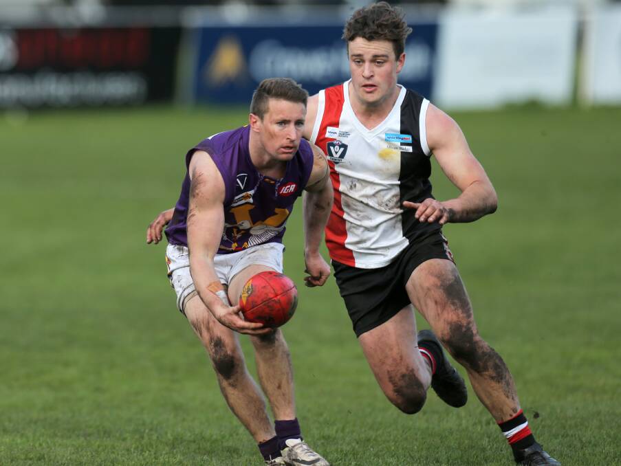 MILESTONE MAN: Port Fairy's Michael Sheehan gets a handball away from Koroit's Jayden Whitehead. Sheehan was in good form in his 200th game. Picture: Rob Gunstone