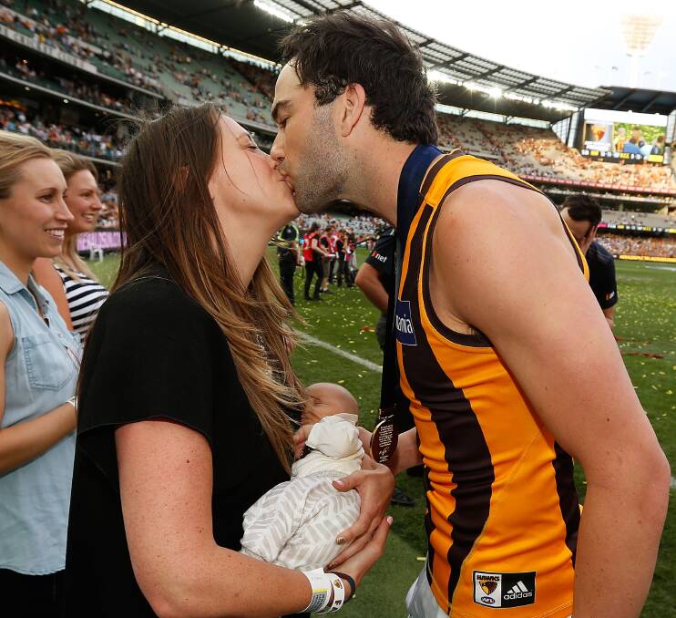 FAMILY MOMENT: Hawthorn star Jordan Lewis and his wife Lucy, holding son Freddie, kiss after the final siren of Saturday's AFL grand final.