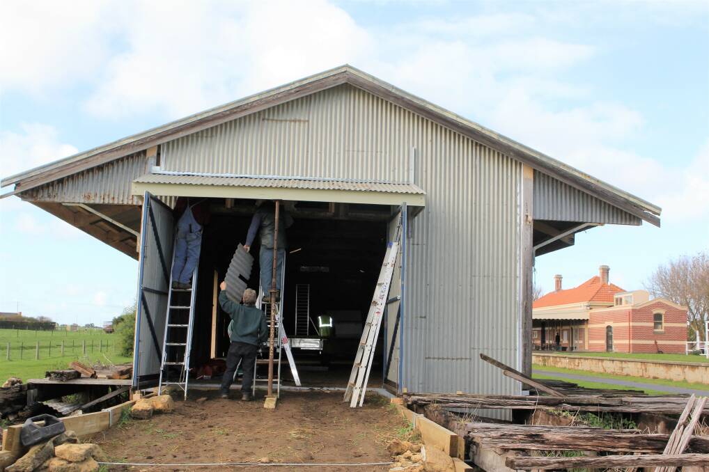 REPAIRS: Members of the friends of the rail trail group work hard on securing the western end of the goods shed at the Koroit Railway Station. Picture: Anthony Brady  