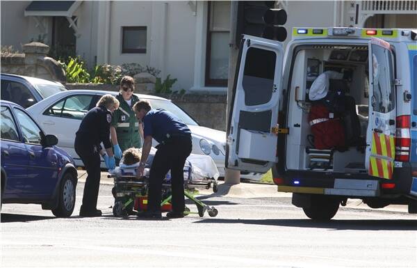 Paramedics treat a cyclist who was involved in a collision with a car on Raglan Parade this morning.