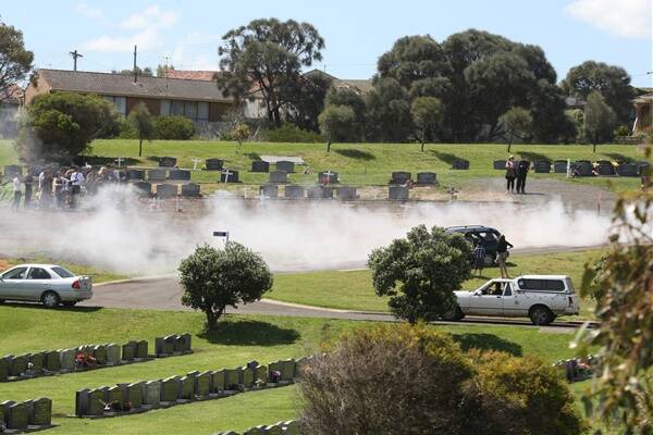 Smoke from the burn-outs drifts across the mourners at the Warrnambool cemetery.