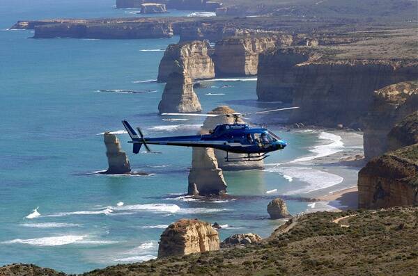 A helicopter takes tourists on a flight over the Twelve Apostles.