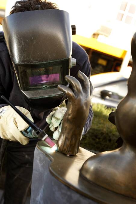 Sculptor Ewan Coates reattaches the missing hand to his piece The Three Pillars of Instant Gratification.