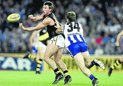 Paul Broderick, playing for Richmond in 2001, handballs while being tackled by the Roos' David King.