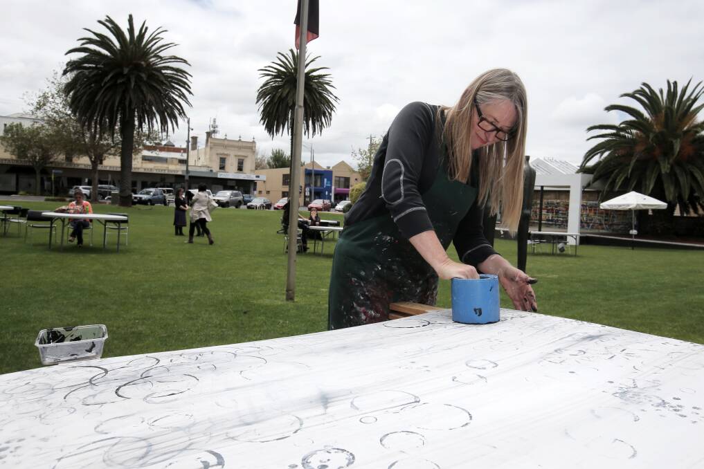 Portland artist Carmel Wallace works on her Arts on the Grass composition using objects found during her walks along Discovery Bay.