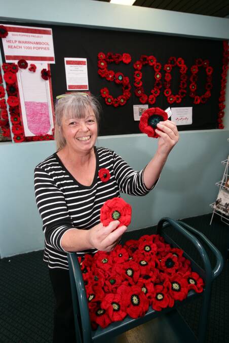Warrnambool Library officer Vicki Cox admires some of the locally-produced knitted Remembrance Day poppies.  