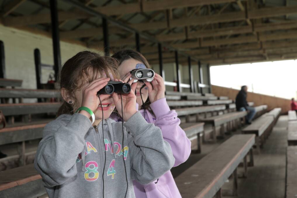 Matilda, 7 and Bridgette Drake, 9, from Warrnambool, train their binoculars on the track action