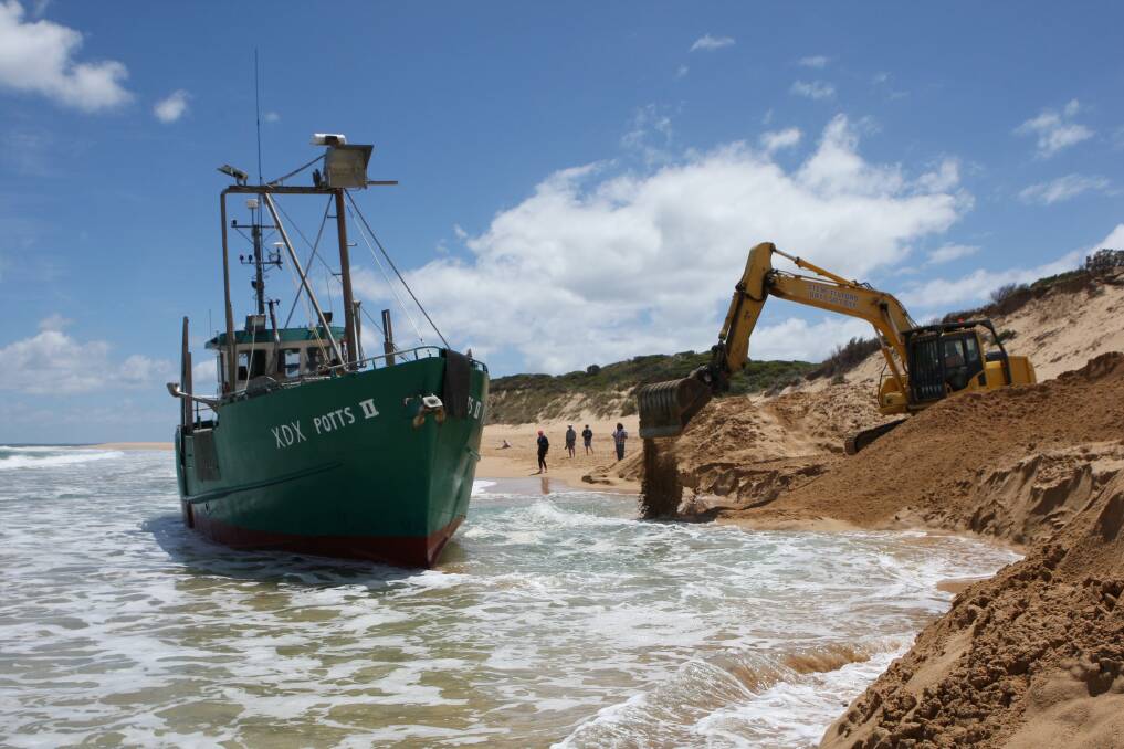 An excavator replaces sand yesterday after a trench was dug to try to refloat a boat stranded on the beach east of Peterborough. 