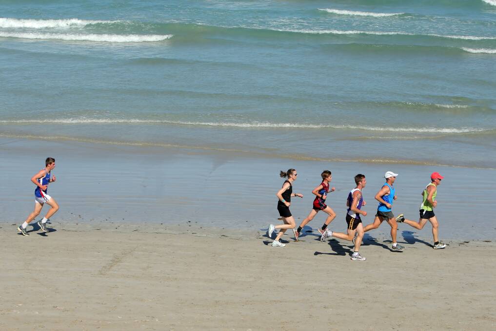 Competitors negotiate the beach leg as part of Port Fairy Football Netball Club’s fun run on Sunday. 