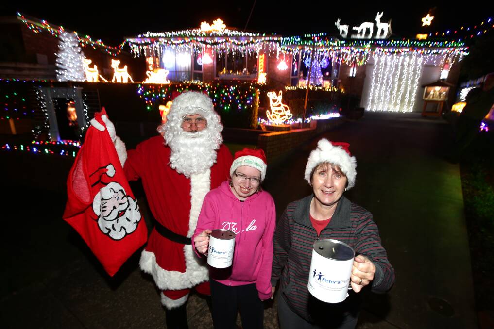 Heath Anderson (left), dressed as Santa, his sister Ellen Anderson and mother Marjorie Anderson put a charitable face to their well-lit Eliza Court home.