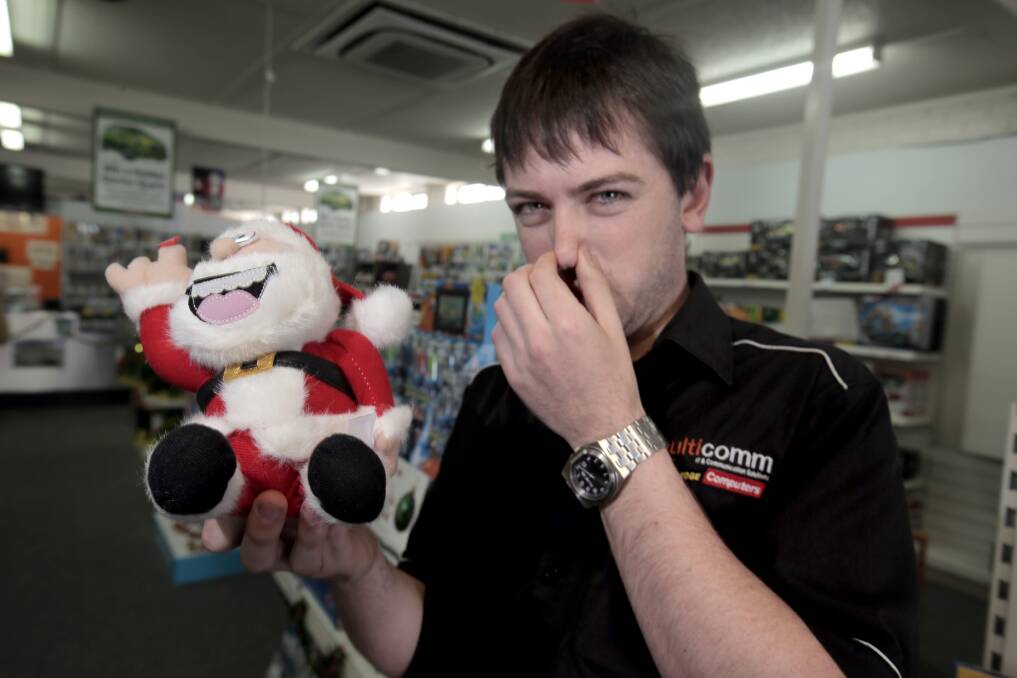 Multicomm electronics staff member Ben Hooker keeps a cheeky Santa toy at arm’s length. 