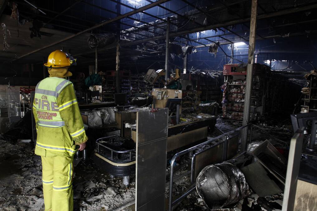 Firefighters survey the damage to Daly’s IGA supermarket in Portland after the fire last year. 