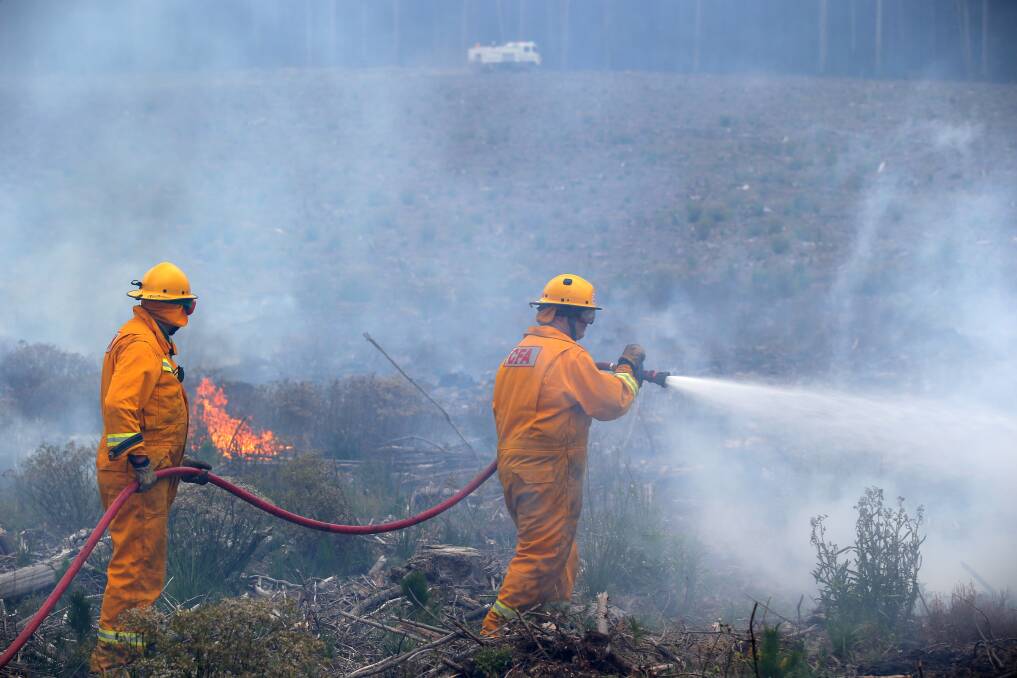 Scorched earth: CFA members hose down flames on land at Drik Drik.