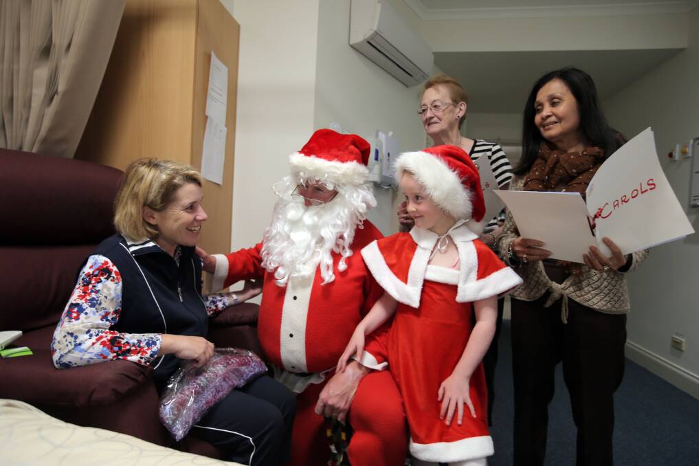 St John of God patient Kate Justin, from Terang, enjoys a visit by Santa, helper Hannah van der Camp, 6, and hospital auxiliary carollers Barb Bourke and Jessica Richardson. 