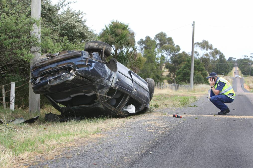 A deployed airbag hangs from the window of the wrecked Commodore sedan on Mount Baimbridge Road.