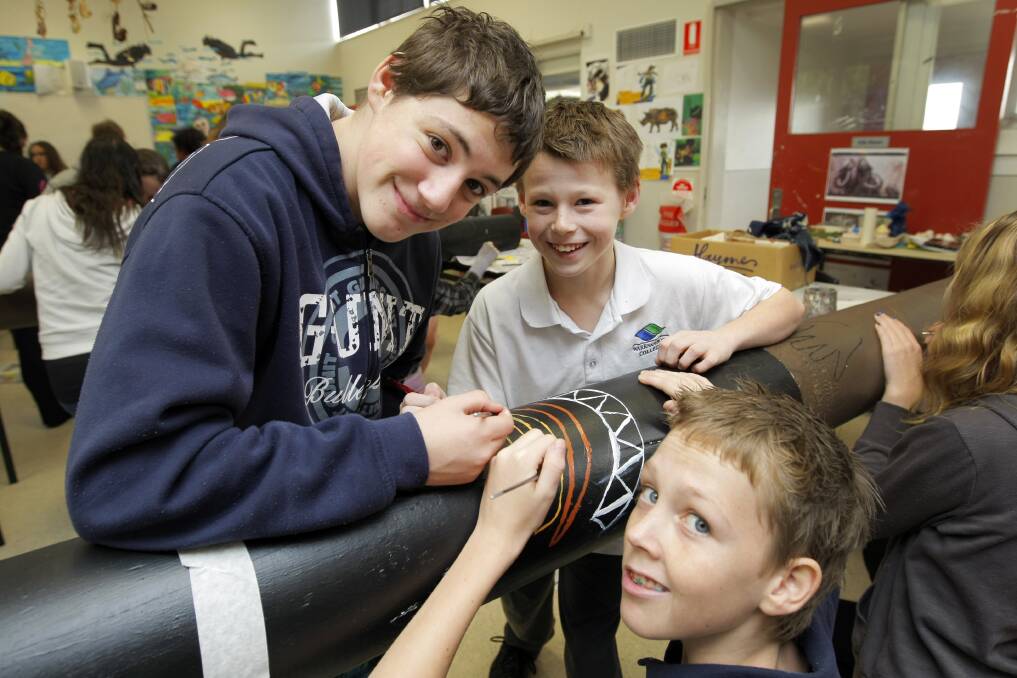 Warrnambool College students Latrell Campbell, 14, Tristan Quarrell, 13, and John Williams, 13, paint a totem pole as part of Reconciliation Week.