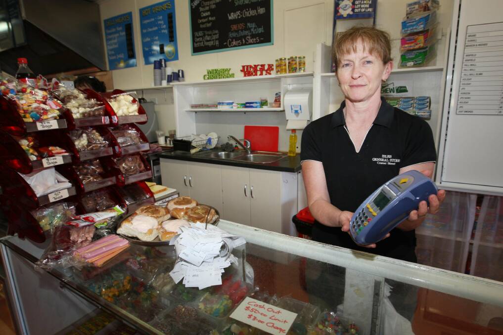 Isles Milk Bar owner Helen McDowell shows a working mobile EFTPOS machine, which most businesses have not had access to.