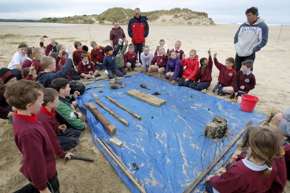 St Pius X Primary School students look at some of the "finds" (planted by a teacher) they dug out of the sand, during their expedition to find the Mahogany Ship.